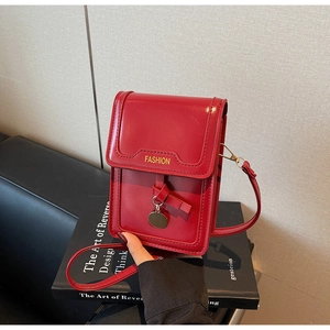 Detail of red leather mini phone bag with knotted tassel and golden metal pendant