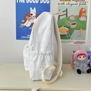 Détail du sac à dos blanc à étoiles avec sangles beiges et poche latérale élastique