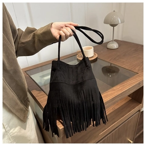 Gros plan du sac seau noir en daim avec franges porté par un mannequin au café