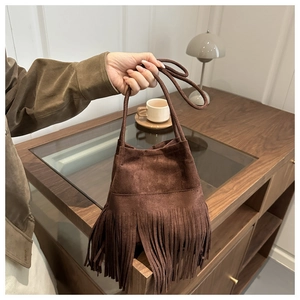 Gros plan du sac seau en daim marron foncé avec de longues franges et détails bohèmes