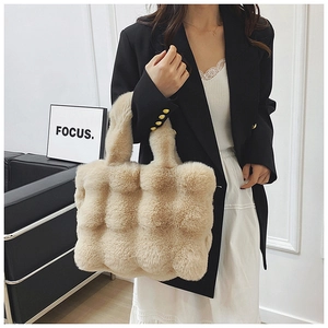 Detail of beige faux fur tote bag with bubble quilted texture shown on a female model