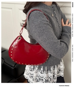 Detail of red crescent moon bag with golden studs and sleek leather texture for women