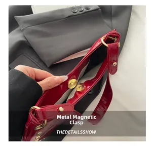 Detail of red patent leather handbag featuring secure metal magnetic snap closure and studs