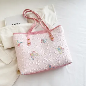 Detailed macro view of a pink quilted tote bag with colorful sequin butterfly embroidery