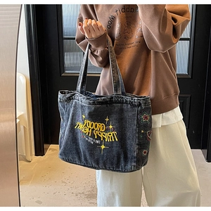 Détail d'un cabas en denim délavé avec broderie colorée et motifs cœur rétro
