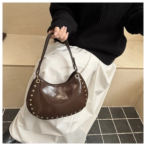 Close-up of a dark brown glossy leather hobo bag with vintage gold rivet detailing