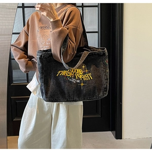 Gros plan sur le sac fourre-tout en toile délavée gris-noir avec broderie jaune