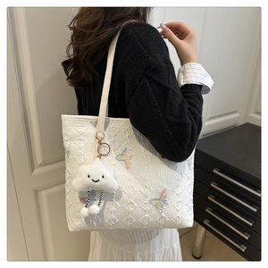 Close-up of white tote bag featuring diamond pattern and colorful butterfly embroidery