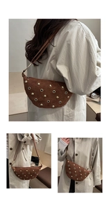 Detail of brown suede crescent bag with gold rivet studs and metallic ring accents