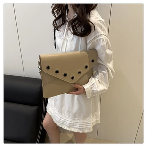 Close-up of light khaki envelope clutch with metal grommets and side D-ring detail
