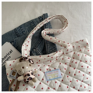 Gros plan du sac fourre-tout matelassé blanc à cœurs rouges avec pendentif en peluche