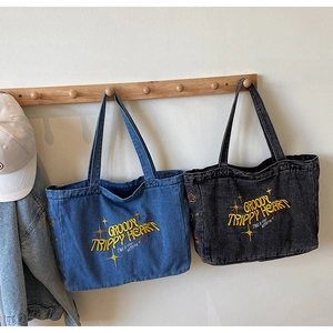 Détails de broderie jaune sur un sac cabas en jean délavé avec motifs d'étoiles