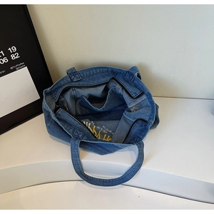 Vue de dessus du sac en denim bleu montrant la doublure intérieure avec broderie et zip