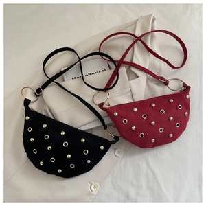 Detailed view of suede shoulder bag featuring gold metal rivets and large ring hardware