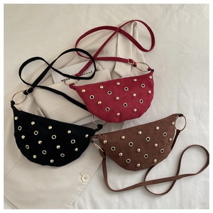 Detail view of suede bags with gold rivets in black, dark red, and brown on white fabric