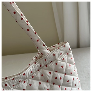 Détail de motifs cœurs rouges sur cabas blanc matelassé avec texture de surpiqûres
