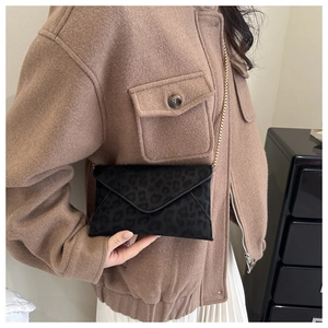 Pochette enveloppe léopard avec chaîne dorée portée par un mannequin de mode
