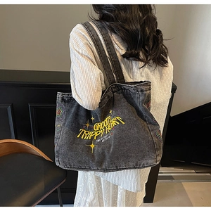 Détail latéral d'un sac cabas en jean délavé avec broderie colorée sur modèle