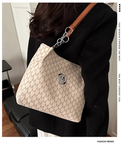 Detail of letter-print tote bag with metallic logo and chain strap on shoulder