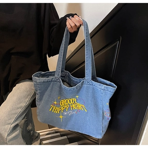 Détail du sac cabas en denim bleu vintage avec broderies et grande capacité de rangement
