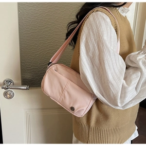 Gros plan d'un sac bandoulière en toile rose clair avec plusieurs poches zippées