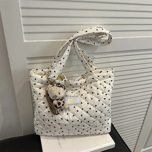 Détail du cabas matelassé blanc avec motifs de cœurs et un charmant pendentif chat