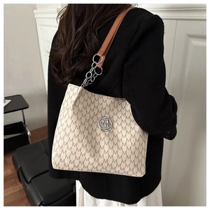 Close-up of M-pattern printed tote bag with silver chain strap and metal logo