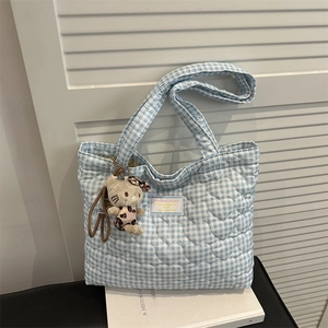 Gros plan d'un sac fourre-tout bleu matelassé à cœurs avec charm chat et étiquette