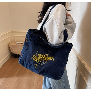 Détail du grand sac cabas en denim bleu foncé avec broderies jaunes et motifs vintage