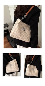 Detail of monogram tote bag with brown M patterns and metallic circular logo charm