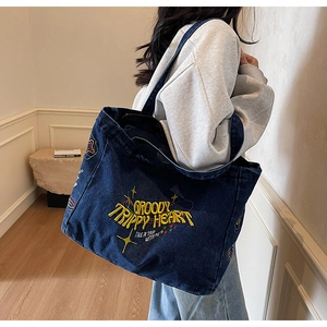 Détail du grand cabas en jean bleu foncé avec broderie colorée au style rétro et artistique