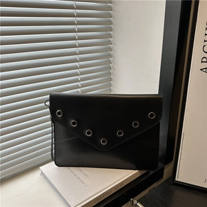 Schicke schwarze Leder-Umschlagtasche mit silbernen Nieten in V-Form auf einem Buch