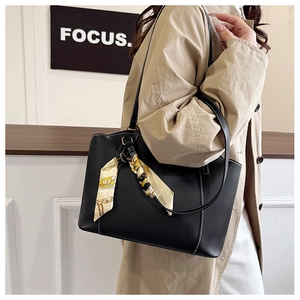 Détail d'un sac cabas en cuir noir avec surpiqûres blanches et foulard en soie élégant