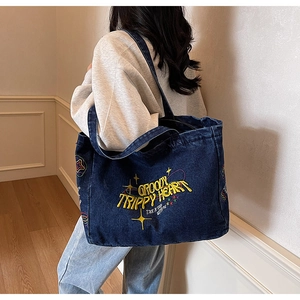 Détail du sac cabas en denim vintage avec broderie jaune et motifs d'étoiles