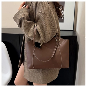 Détail d'un sac cabas en cuir marron foncé avec surpiqûres blanches et foulard en soie