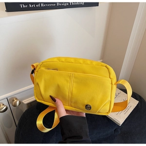 Détail d'un sac bandoulière en toile jaune vif avec multi-poches et sangle réglable