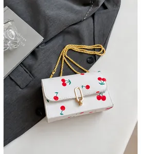 Close-up of white cherry print handbag with golden twist lock and metal chain strap