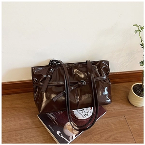 Detail of the high-gloss dark brown patent leather tote with decorative buckle strap