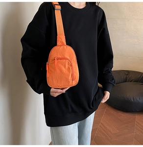 Détail d'un sac bandoulière en nylon orange vif avec sangle réglable sur le mannequin
