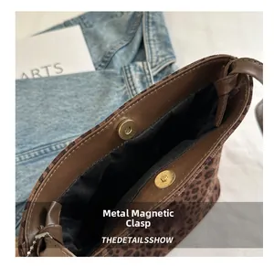 Detalle del bolso de leopardo con cierre magnético de metal y ribetes de cuero marrón