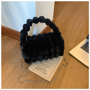 Détail du sac à main noir en peluche avec poignée à pompons et bandoulière chaîne argent