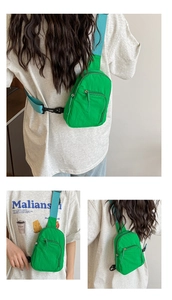Détail du sac bandoulière en nylon vert avec sangle bleue et doubles poches zippées