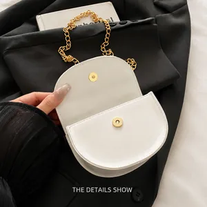 Detail shot of the gold magnetic closure and white leather flap on the saddle bag