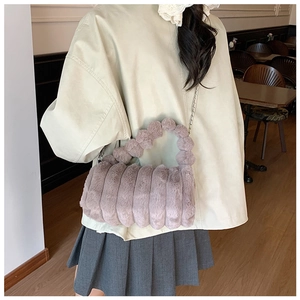 Détail du sac à main en peluche mauve avec texture matelassée et poignée à pompons
