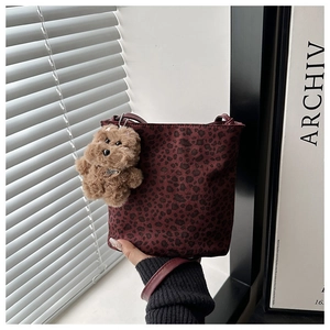 Detalle del bolso de hombro burdeos con estampado de leopardo y colgante de perro de peluche