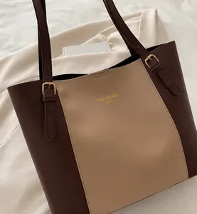 Detail of color-block tote bag with gold brand logo and adjustable leather shoulder strap