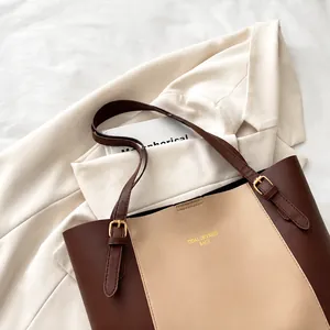 Detail of color-block tote bag featuring adjustable strap and gold metal buckles