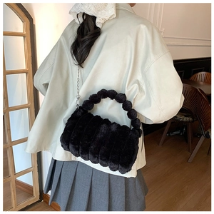 Détail du sac à main en fausse fourrure noire avec poignée boule et chaîne argentée