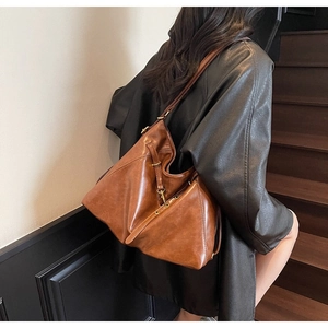 Detail of vintage brown leather tote bag showing metallic buckles and adjustable strap
