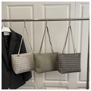 Detailoverzicht van geweven draagtassen in beige, groen en bruin met kettingriemen